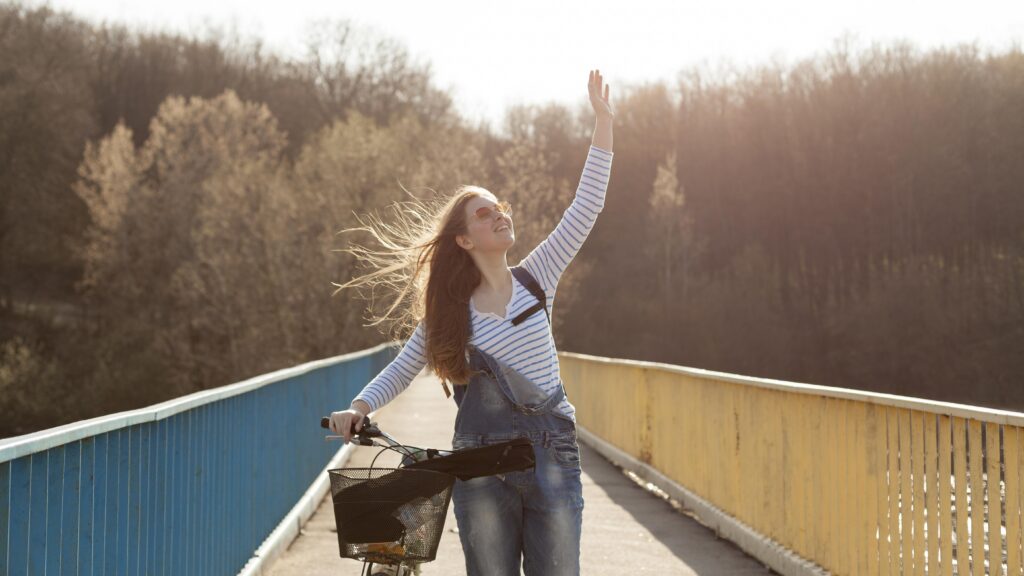 carefree woman posing with bicycle bridge