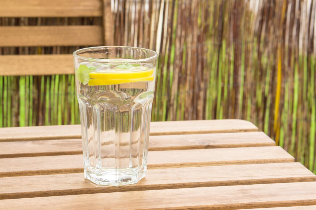 closeup shot of a glass of water with lemon and mint on a wooden bench
