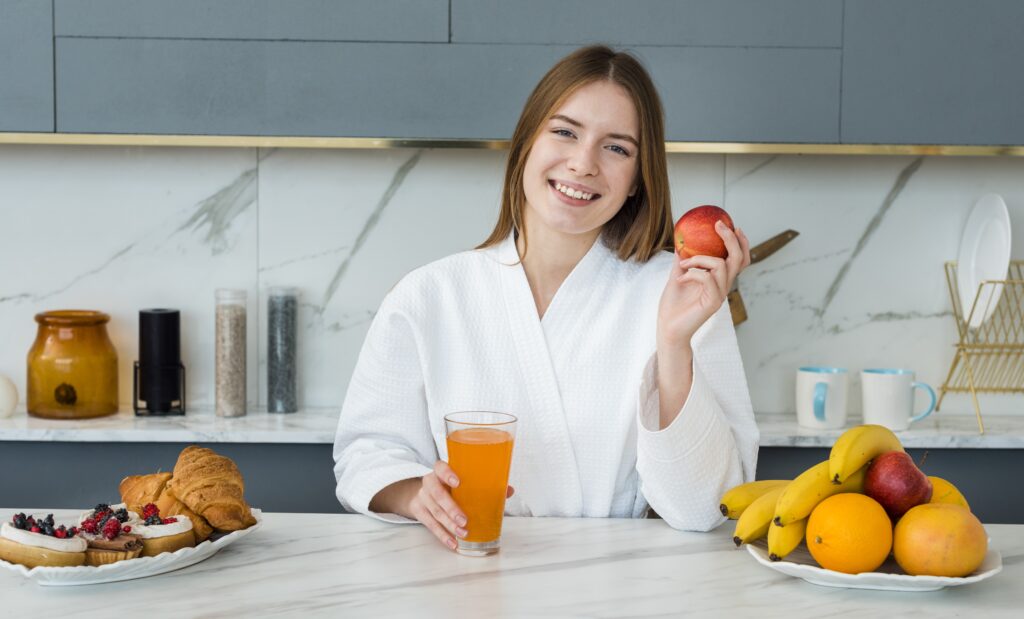 front view woman bathrobe holding apple