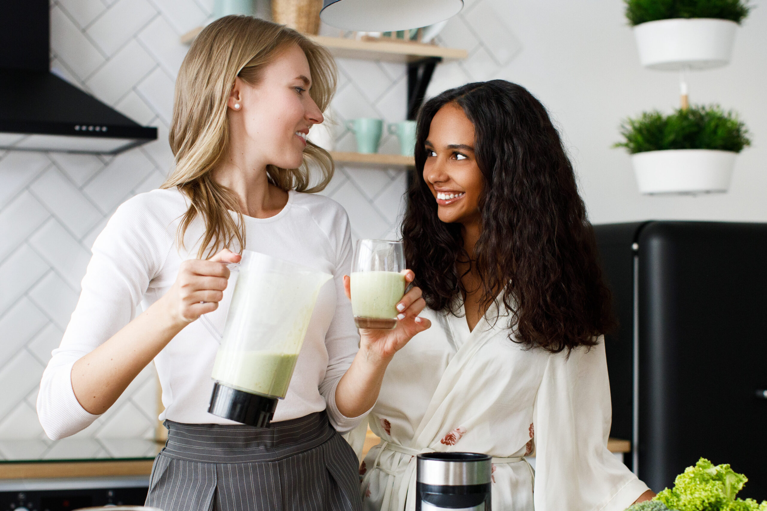 caucasian woman is pouring milkshake in a glass and african girl