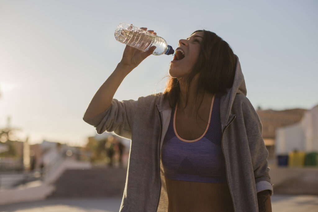woman hoodie drinking water standing outside