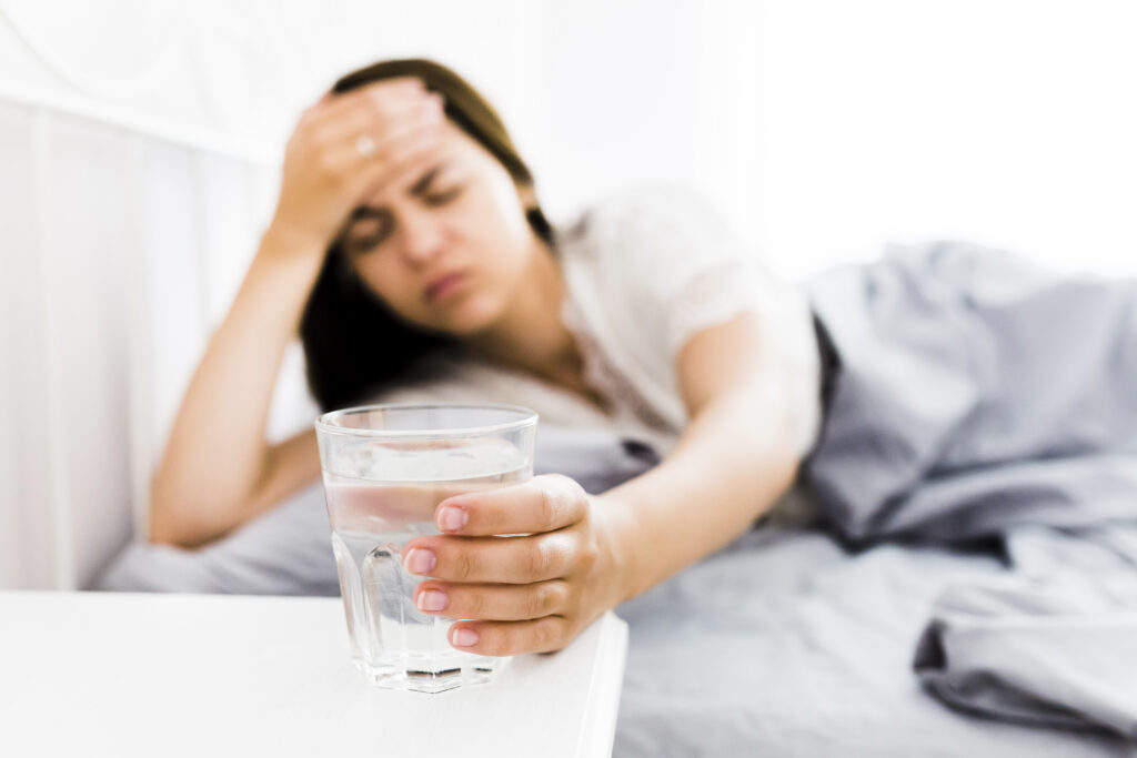 woman with headache taking glass water